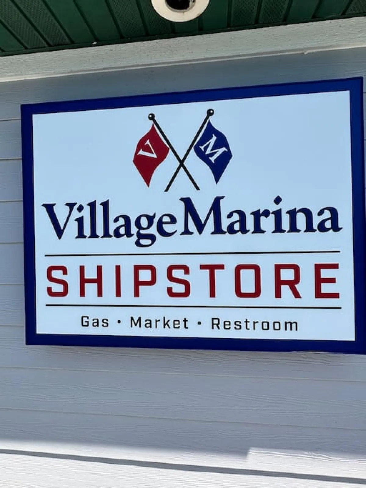 This image features the Village Marina sign with nautical flags and the Shipstore title, signaling the nearby marina's amenities such as boating services, supply shopping, and local dining options.