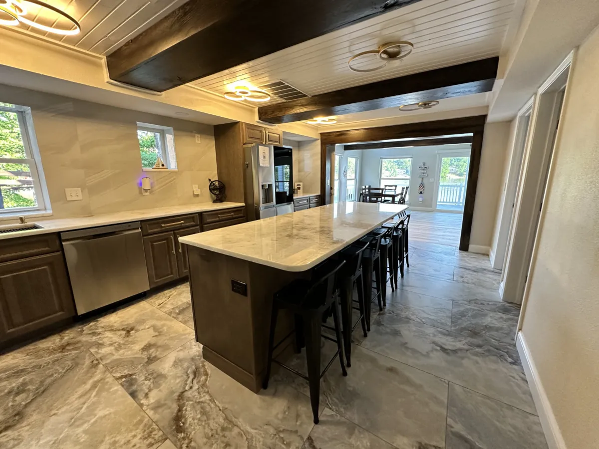 A modern kitchen with a prominent large island surrounded by seating, stainless steel appliances, and windows that flood the space with natural light. The setup encourages conversation and social interaction while cooking, making it ideal for group breakfasts or evening feasts.